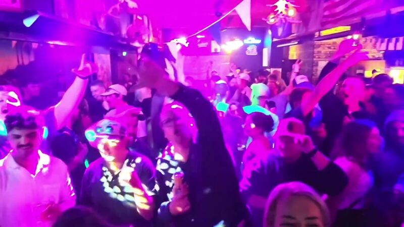 A packed dance floor under pink and blue lights