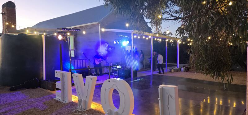 The light rig at an outdoor party at dusk under festoon lights